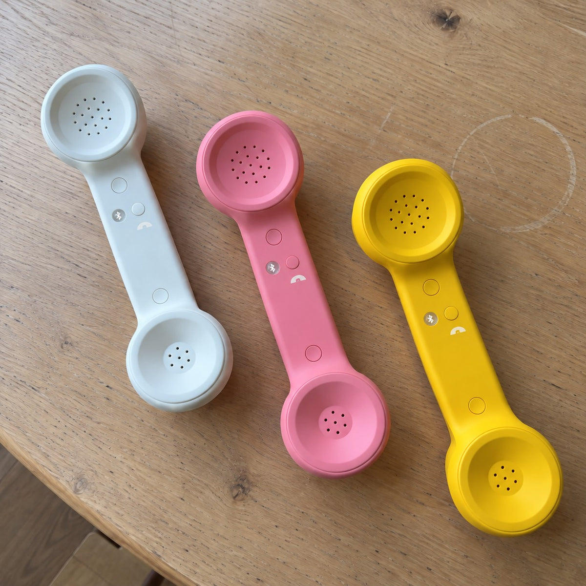 Customer photo: White, Pink and Yellow Novapix Bluetooth Retro Handsets on a wooden table